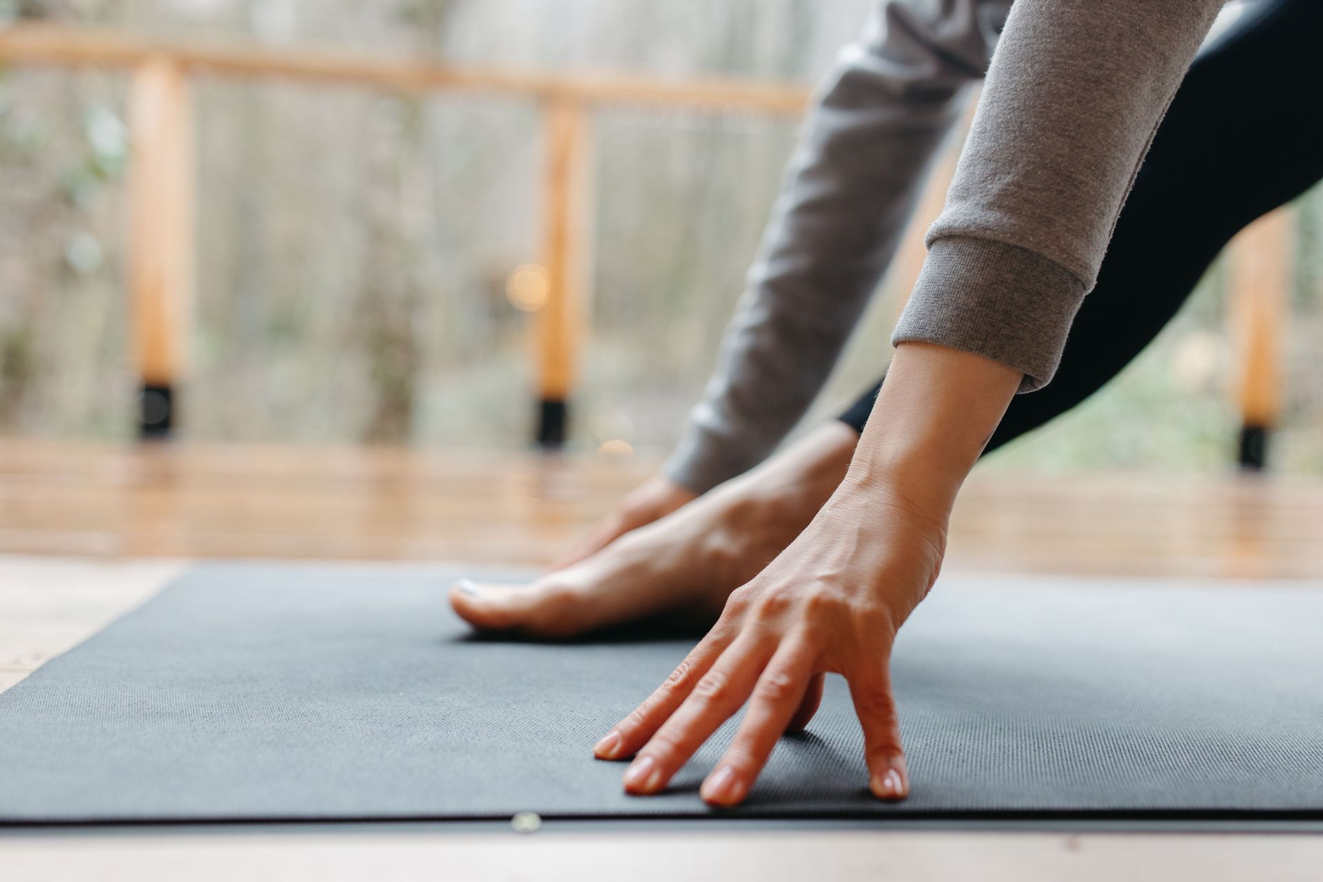 A person stretches their hand and foot on a yoga mat indoors, focusing on wellness.